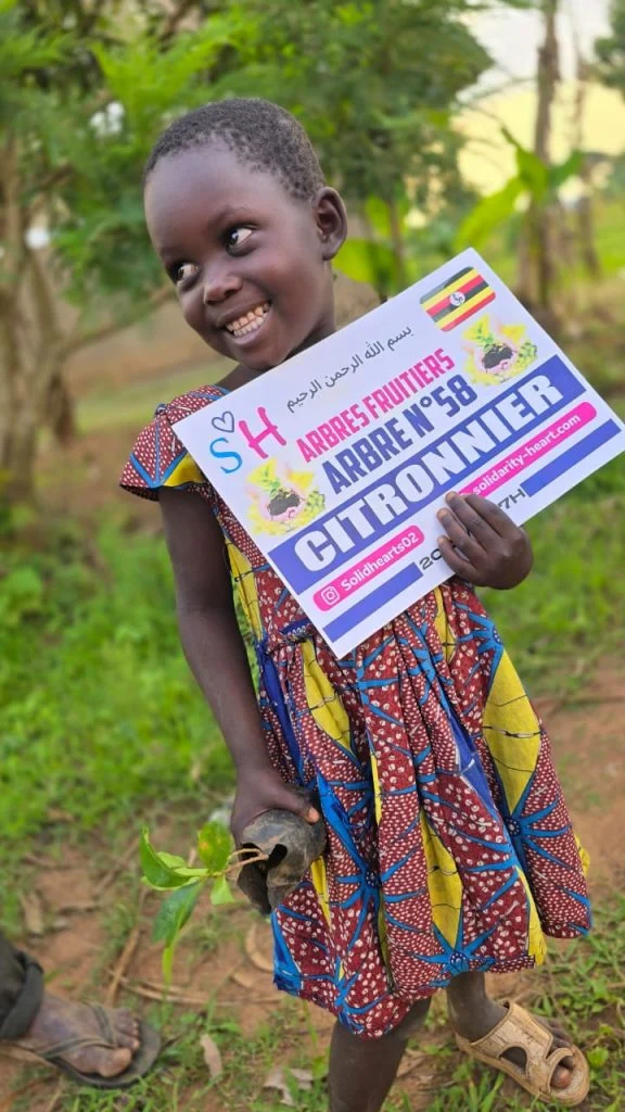Enfant tenant un plant de citronnier et sa plaque de plantation.